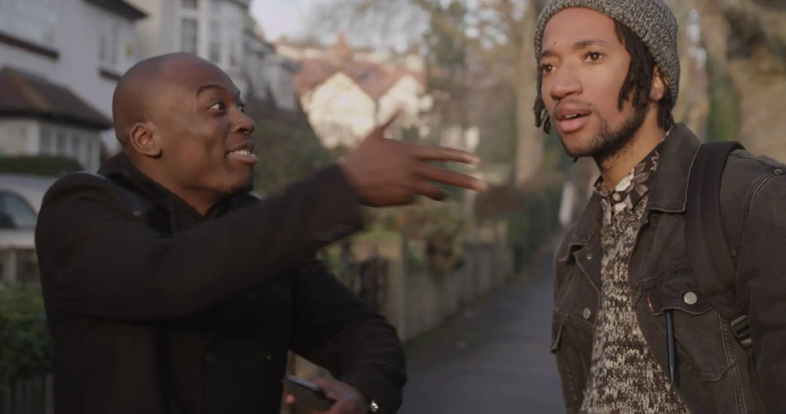 Eddie Kadi performing with a collaborator in an early online comedy film